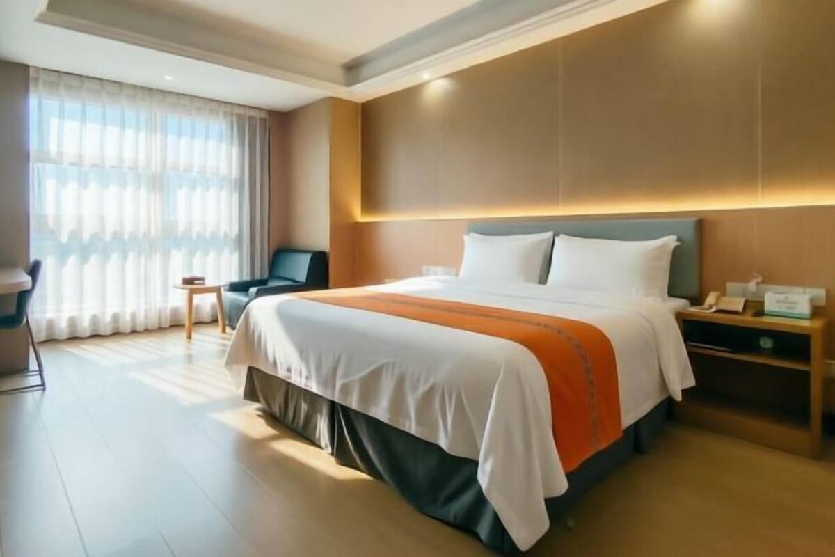 Una habitación de hotel con una cama grande, una mesita de noche, una silla y un escritorio.