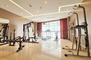 A gym with various exercise equipment, a large window with curtains, and a polished floor. - Lei Da Sen Hotel (Wenling)