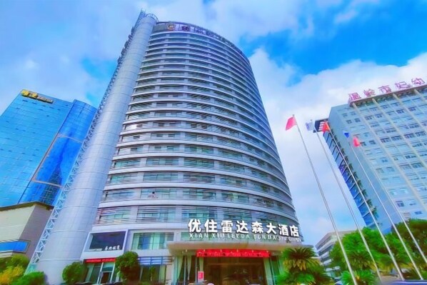 Un edificio hotelero alto y curvo con una entrada destacada y señalización.