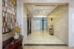 Un hall de hotel con piso de mármol, una recepción y una pantalla montada en la pared.