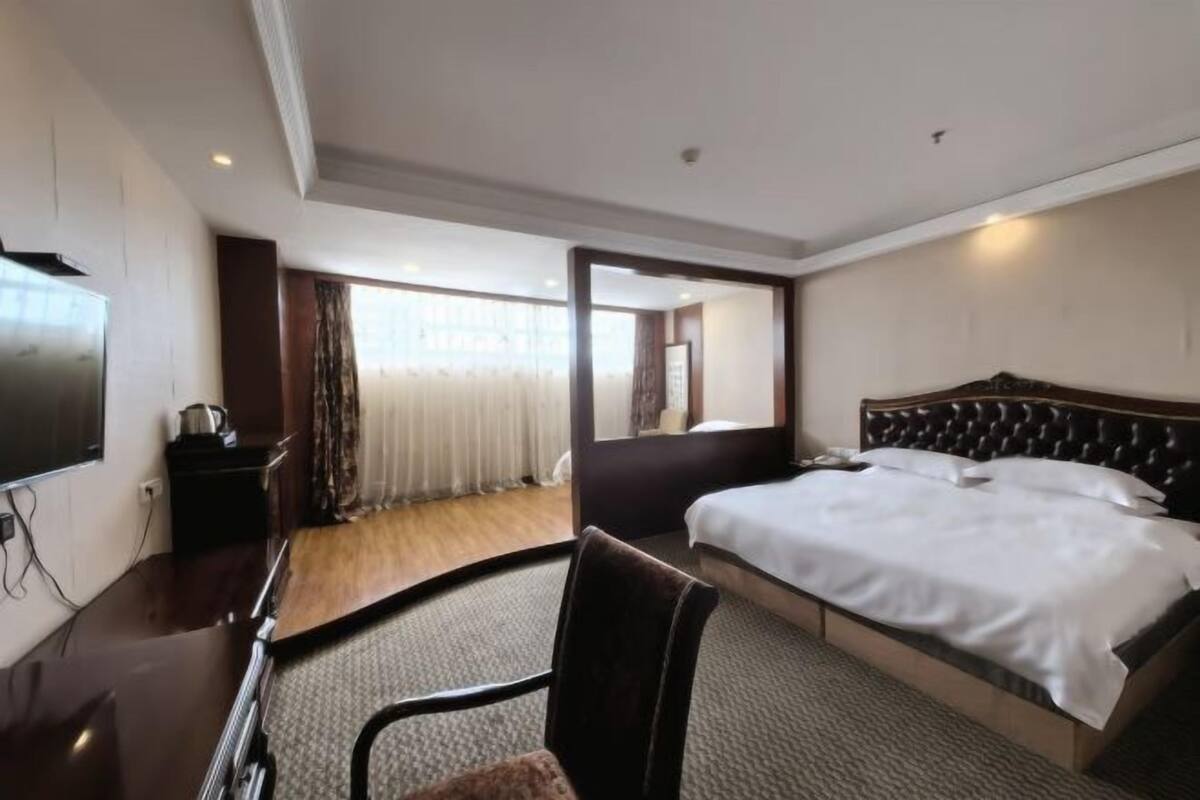 Habitación de hotel con una cama grande, televisor de pantalla plana, escritorio y una silla.