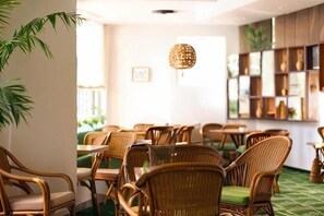 A restaurant with wicker chairs, a green carpet, and a bookshelf in the background. - Lei Da Sen Hotel (Wenling)