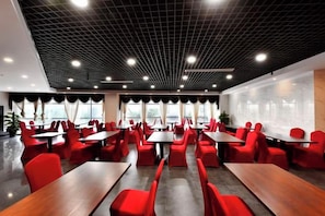 A modern dining area with red chairs and tables, a black ceiling with grid pattern, and large windows. - Lei Da Sen Hotel (Wenling)