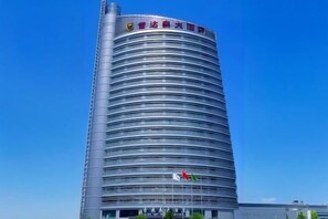 A tall, cylindrical building with horizontal lines, a flag, and a sign with Chinese characters. - Lei Da Sen Hotel (Wenling)