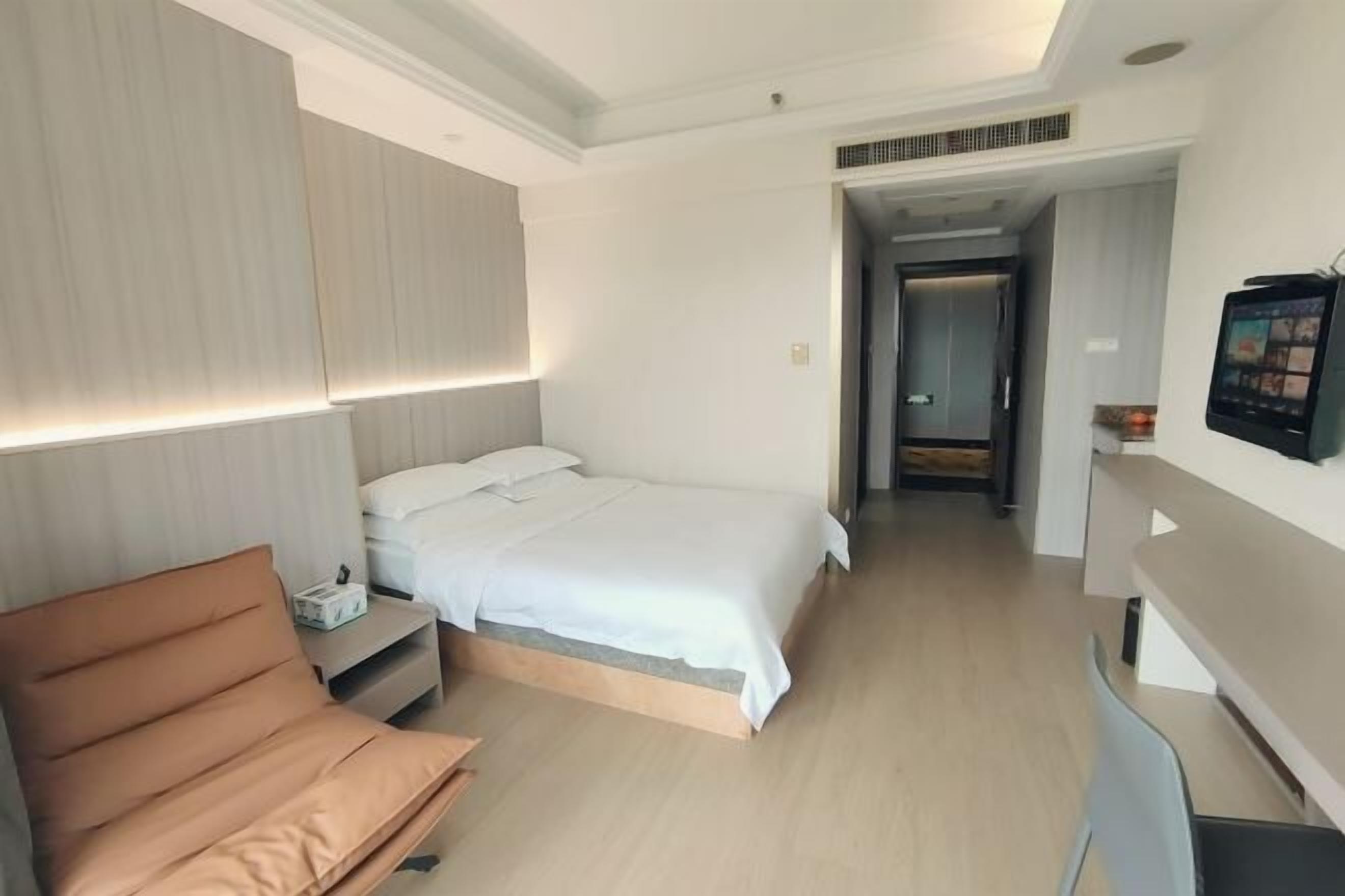 Una habitación de hotel moderna con cama, sofá, escritorio y televisor.