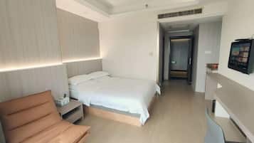 Una habitación de hotel moderna con cama, sofá, escritorio y televisor.