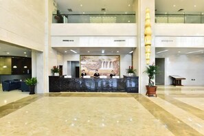 A hotel lobby with a reception desk, seating area, and a large artwork on the wall. - Lei Da Sen Hotel (Wenling)