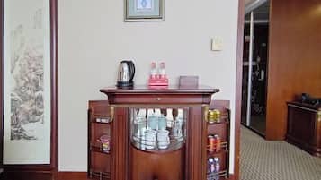 Un mueble de madera con estantes de vidrio que contiene utensilios de cocina, una obra de arte enmarcada en la pared y un piso alfombrado.