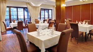 Un restaurante con varias mesas dispuestas para comer, ventanas amplias y paneles de madera en las paredes.