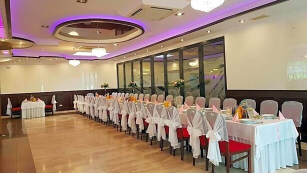 Un salón de banquetes con filas de mesas, sillas y una pantalla grande.