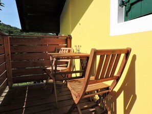 Una terraza de madera con dos sillas y una mesa de madera.