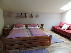 Un dormitorio con dos camas de madera, un sofá rojo y un tragaluz.