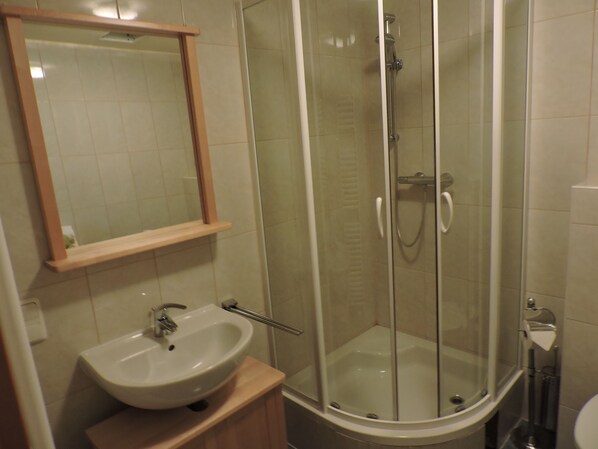 Ein Badezimmer mit einem weißen Waschbecken, einem Spiegel und einer Duschkabine.