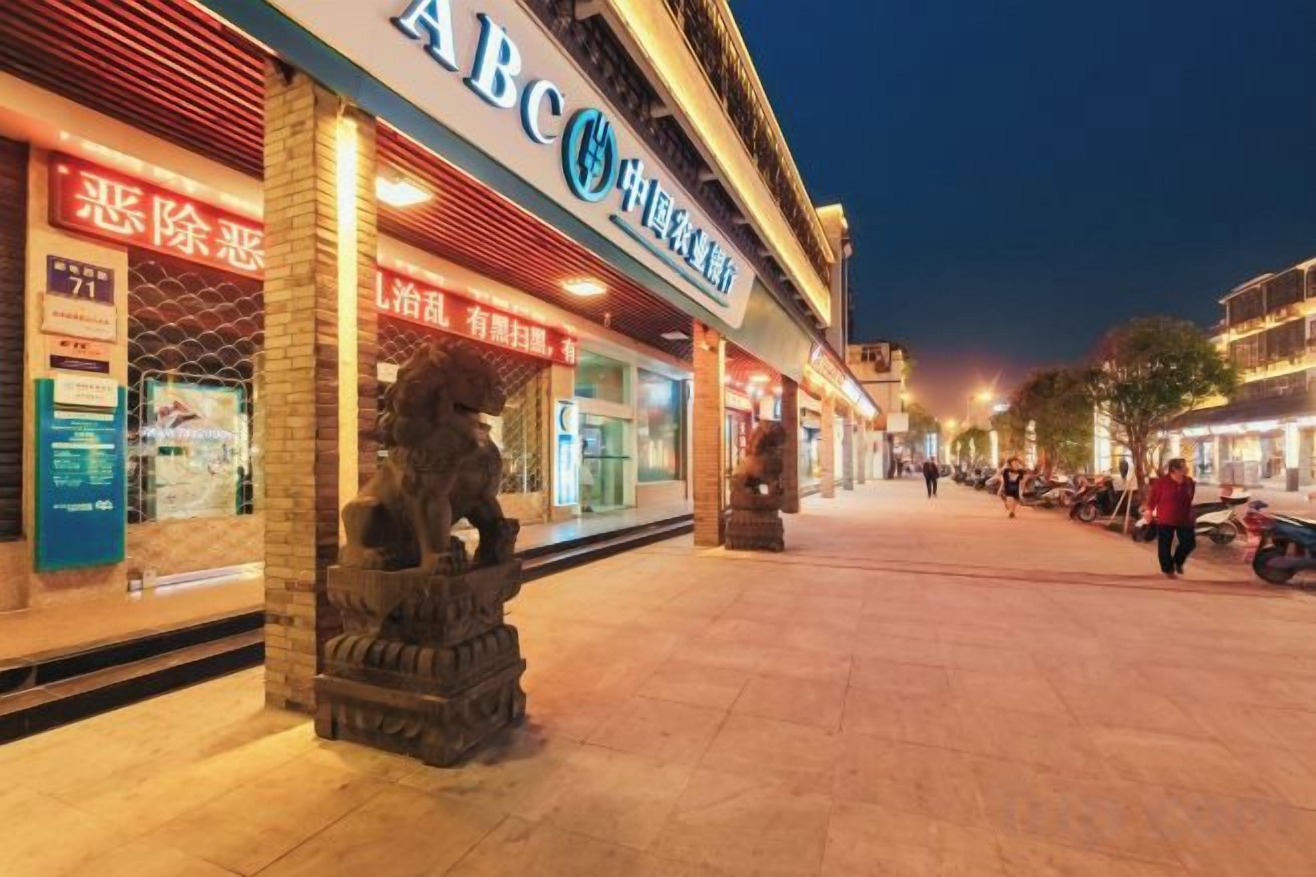 A street with shops and a statue of a lion.