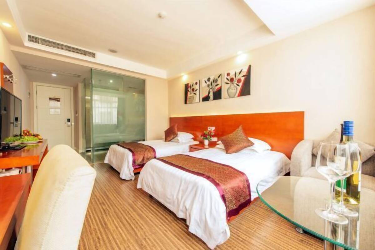 A hotel room with two beds, a glass table, a TV, and a dining area.