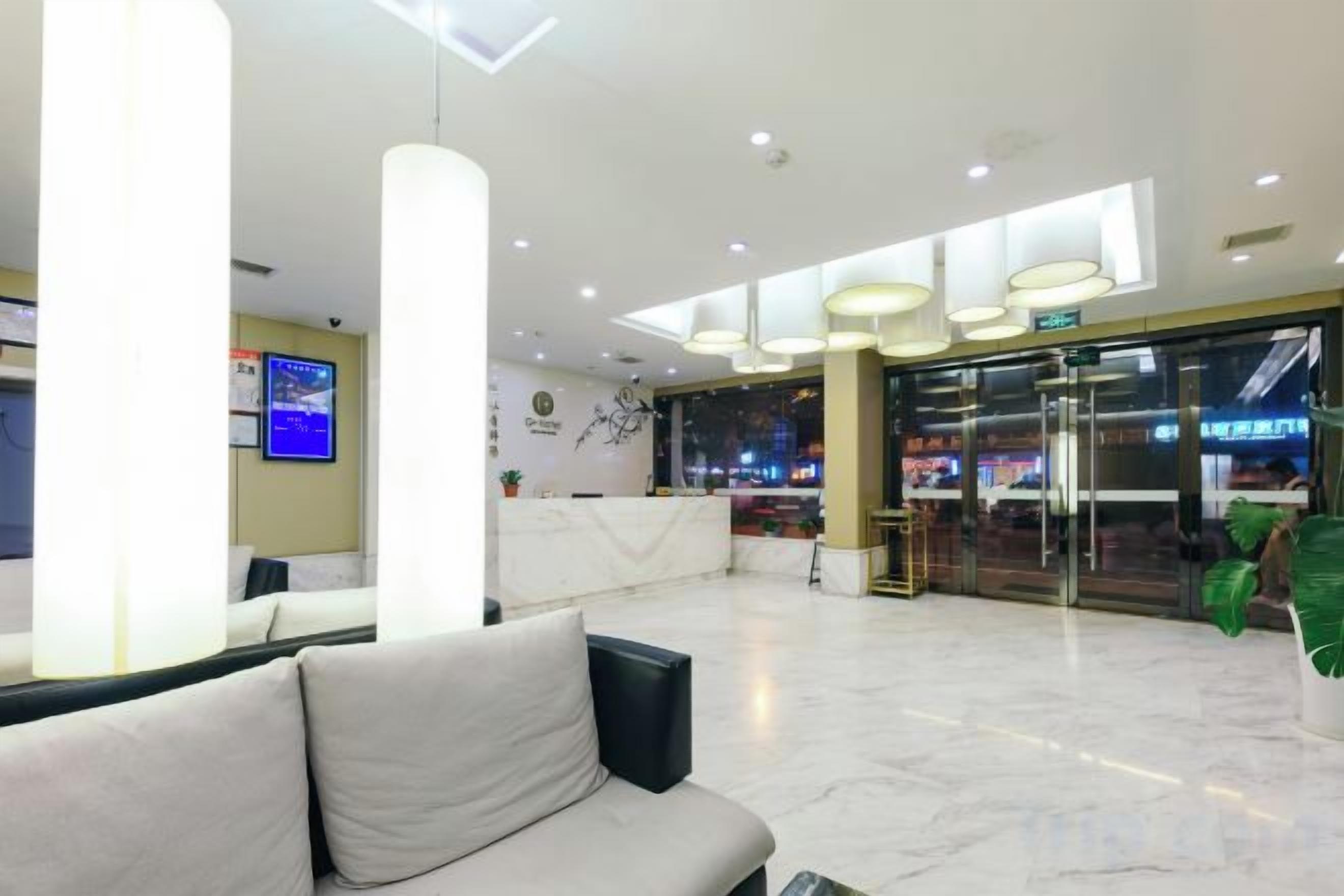 Eine Hotelhalle mit einer Rezeption, einer Sitzecke und einer Treppe zu einer oberen Etage.