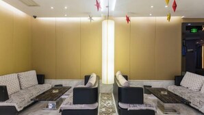 A modern lounge area with sofas and coffee tables, a central light fixture, and decorative hanging elements. - Xitang Hotel (Jiaxing)