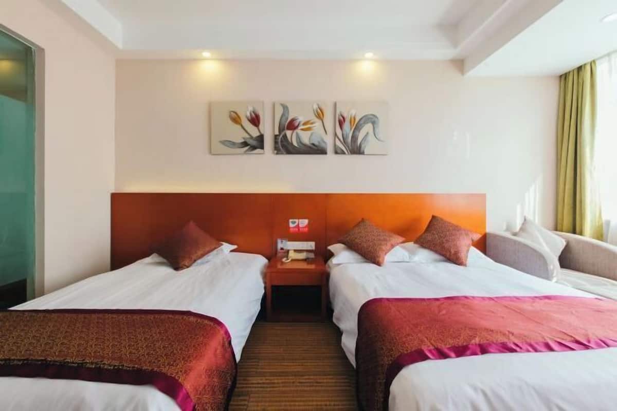 A hotel room with two beds, a headboard, artwork on the wall, and a nightstand.