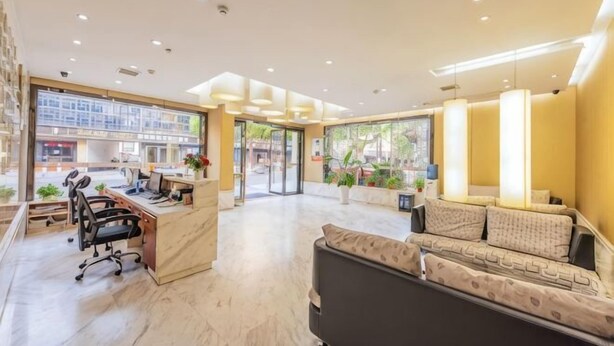 A hotel lobby with a reception desk, seating area, and large windows. - Xitang Hotel (Jiaxing)