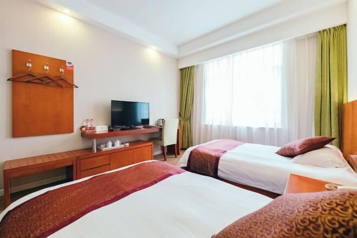 A hotel room with two beds, a TV, a desk, and a wardrobe.