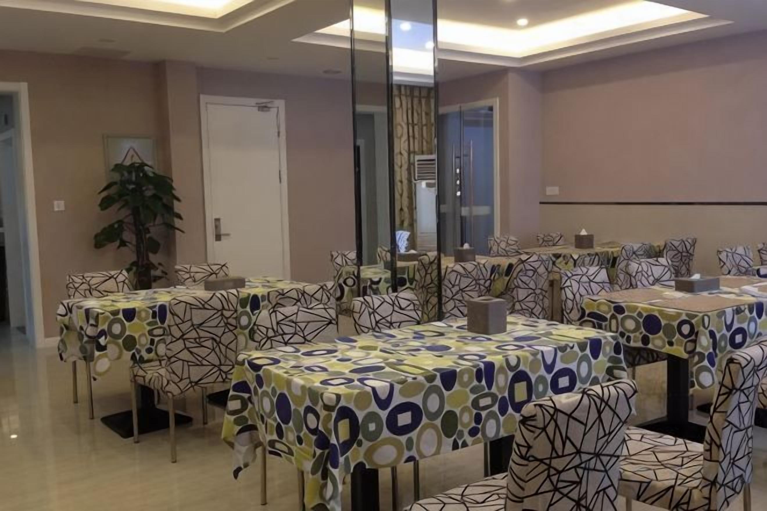 A dining area with multiple tables and chairs, a large mirror, and a potted plant.