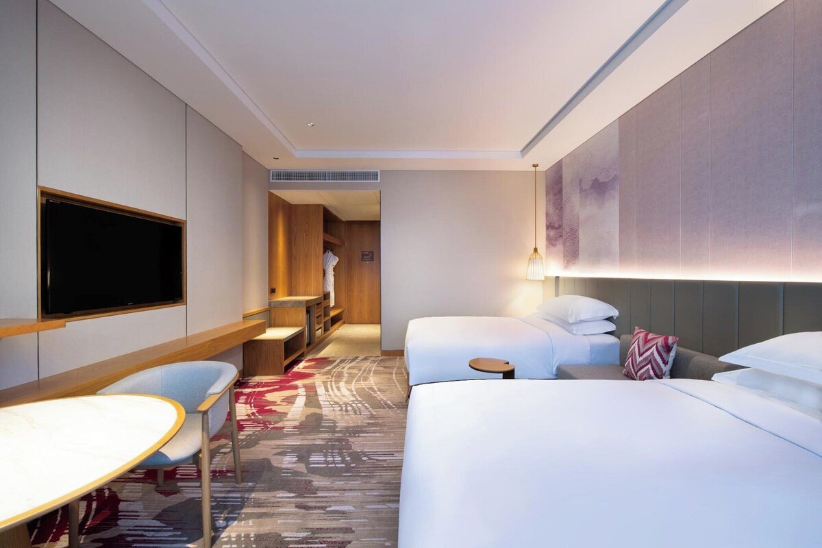Ein Hotelzimmer mit einem großen Bett, einem Schreibtisch, einem Sessel, einem Fernseher und einem Badezimmer.
