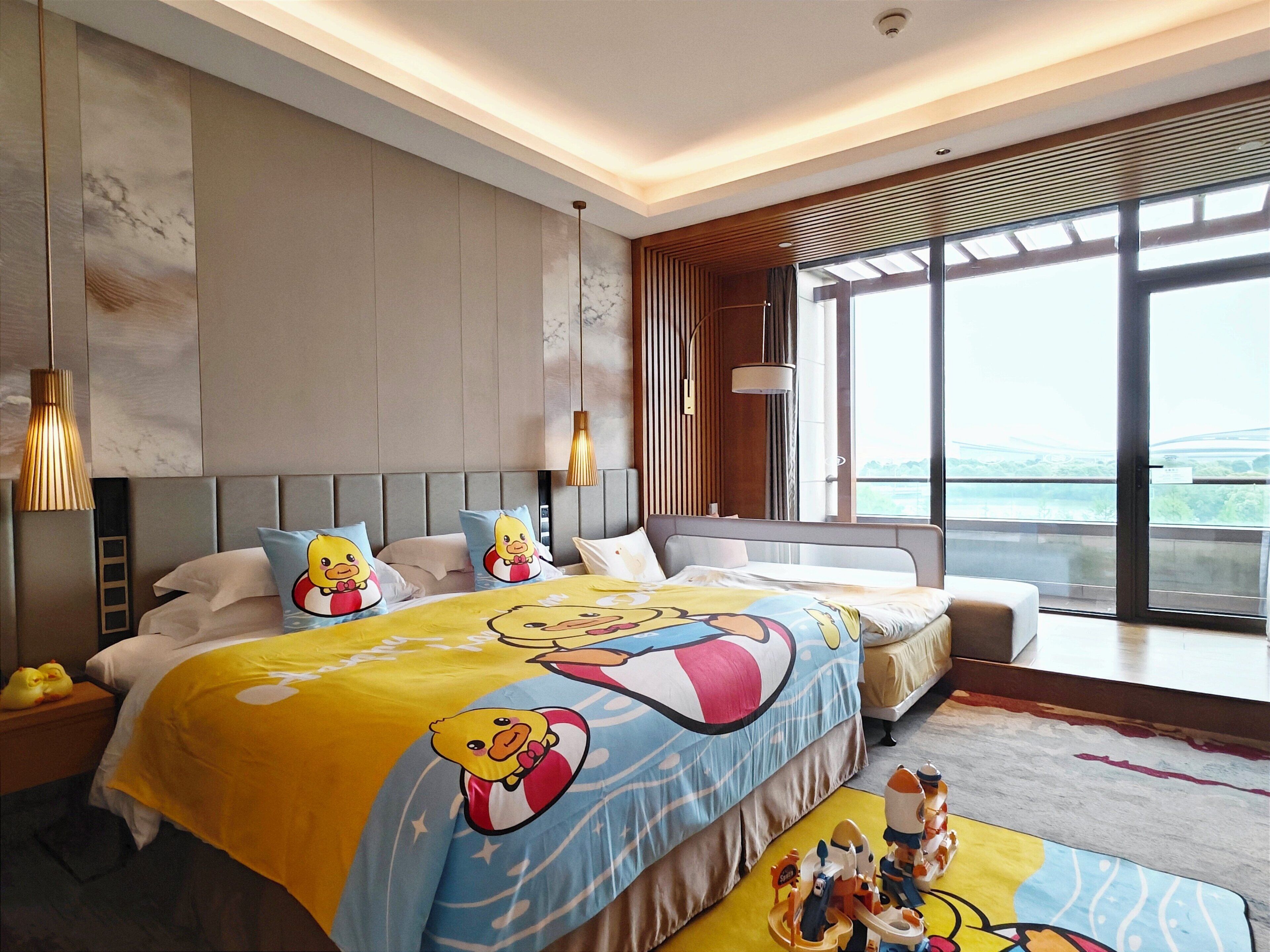 Ein modernes Schlafzimmer mit einem großen Bett, Blick ins Freie und Stadtansicht durch das Fenster.