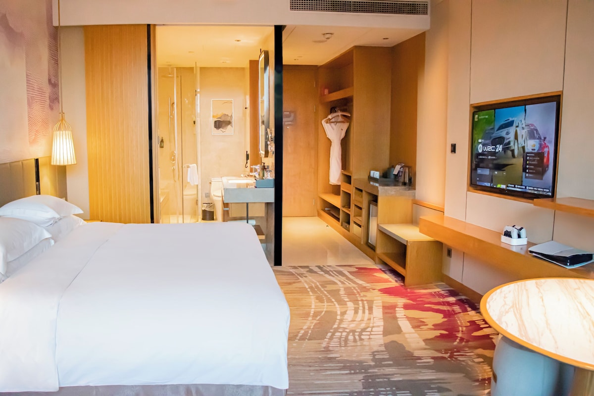 Habitación de hotel con cama, televisión, escritorio y baño.