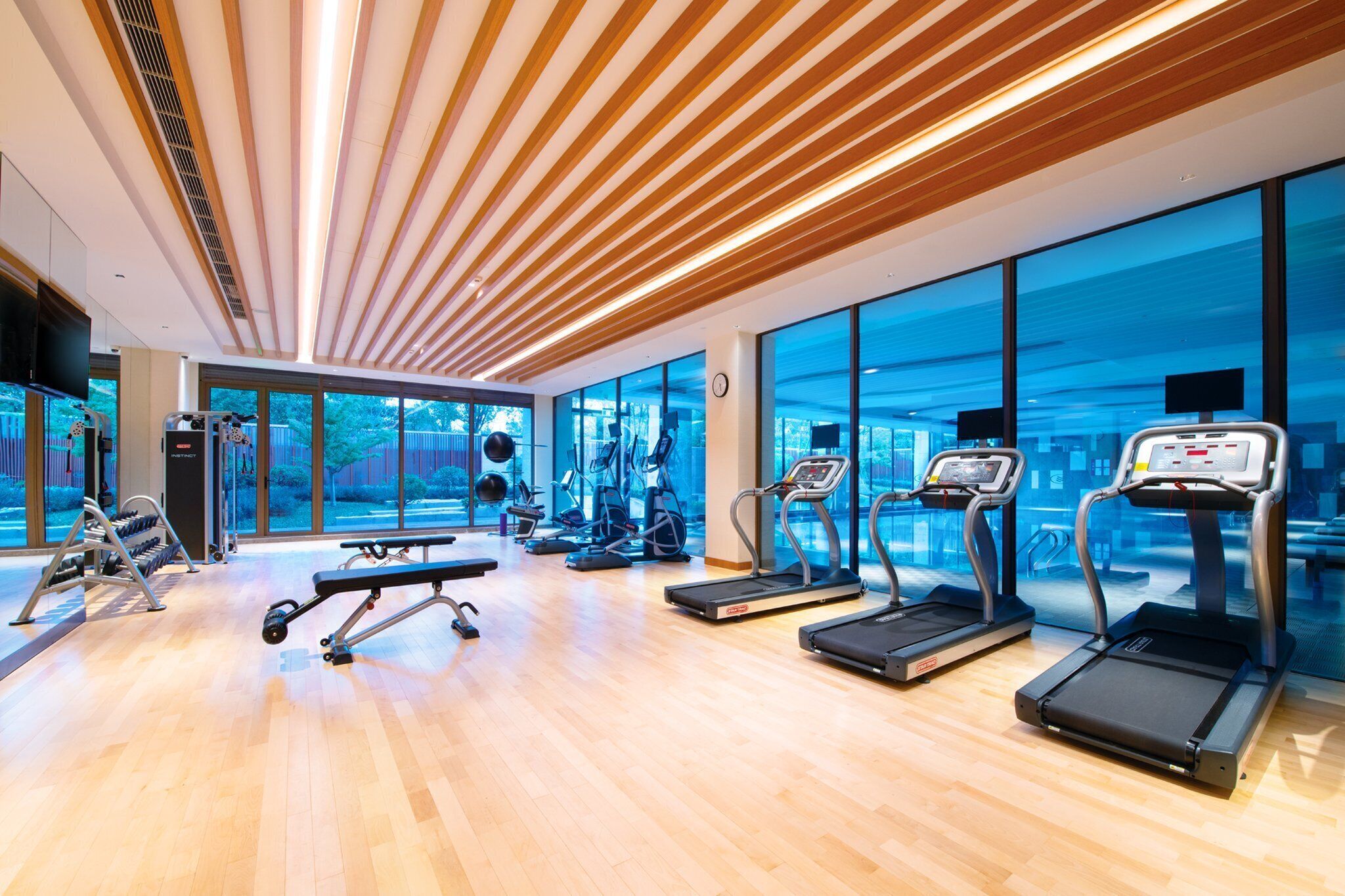 Un gimnasio moderno con cintas de correr, una banca para press de pesas y máquinas de pesas.