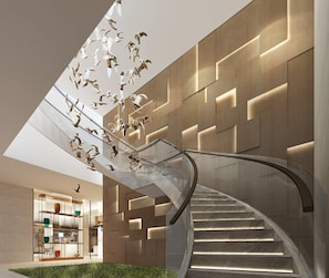 A modern interior with a curved staircase, a glass railing, and a wall with geometric patterns.