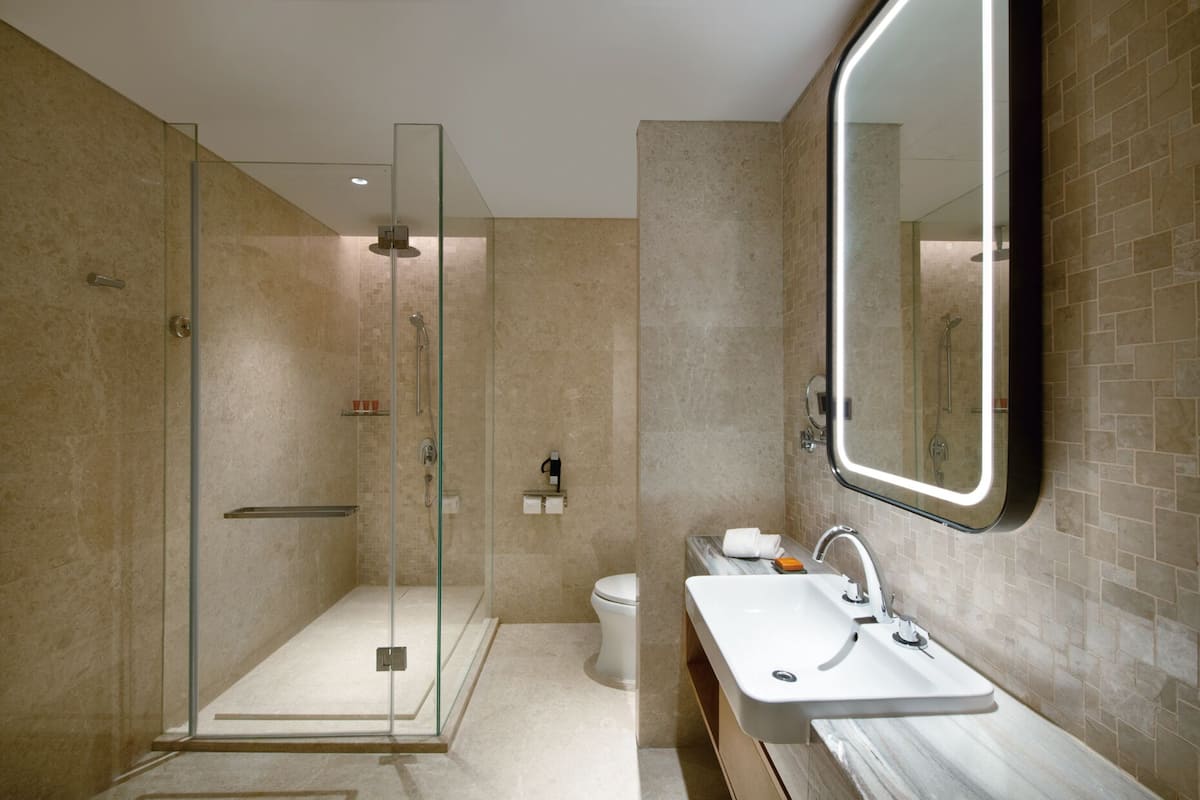 A modern bathroom with a glass-enclosed shower, a white sink, and a large mirror.