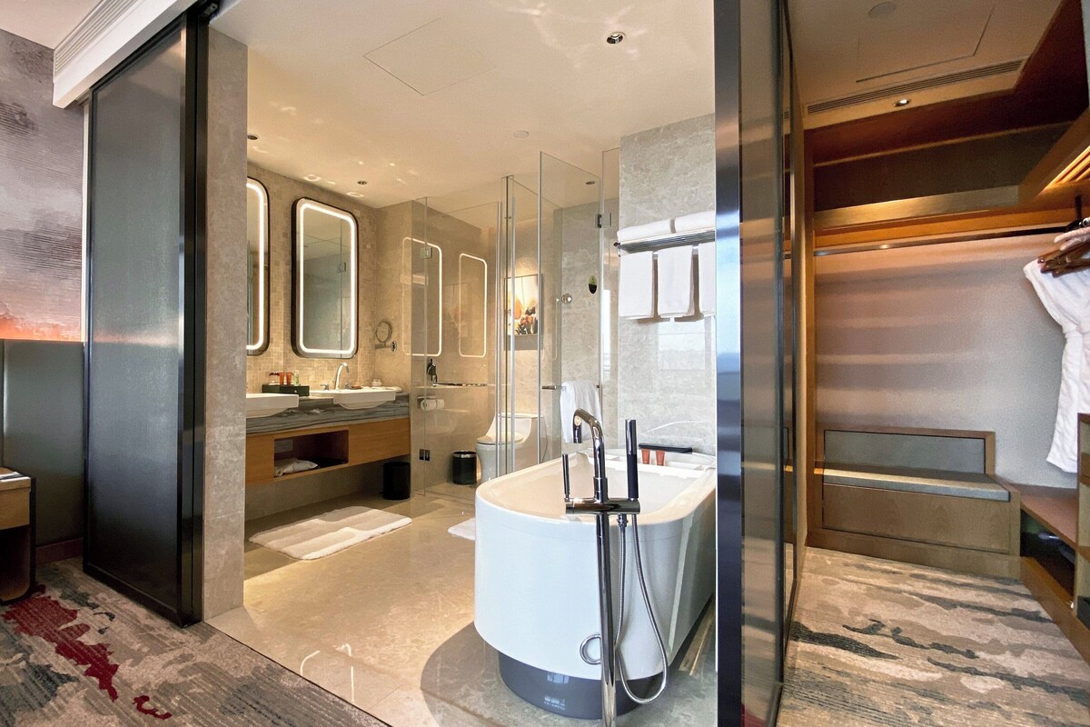 A modern bathroom with a large bathtub, a glass-enclosed shower, and a vanity with a mirror.