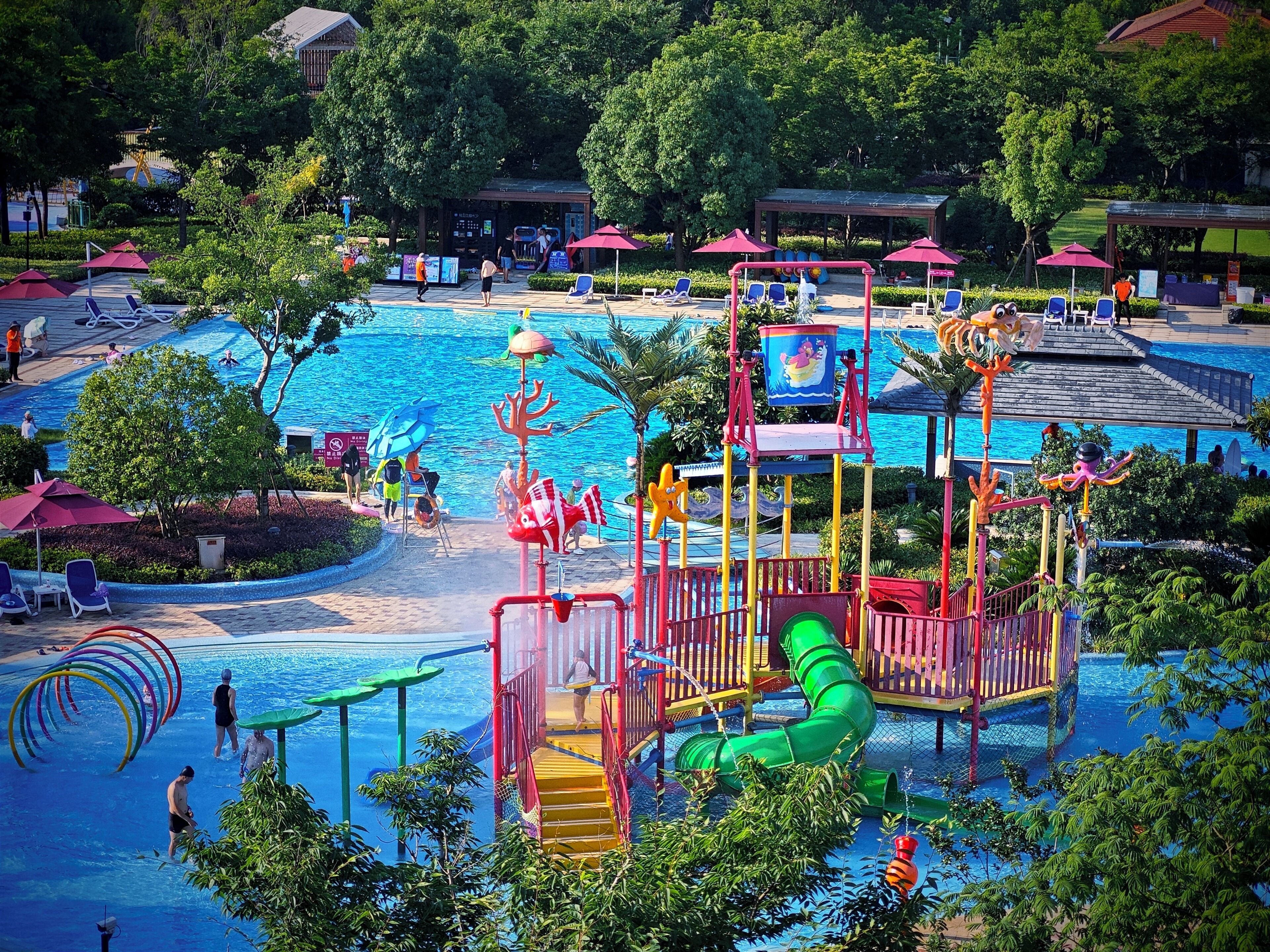 A water park with a swimming pool, slides, and play structures.