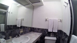 Un baño con un lavamanos blanco, inodoro y espejo.