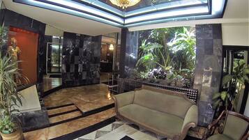 A lobby with a checkered floor, a sofa, a chandelier, and a reception desk.