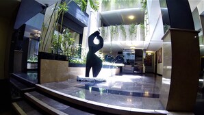 Un moderno vestíbulo con una fuente central, una escalera y plantas de interior.