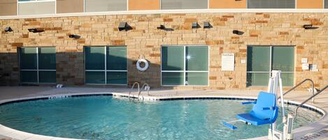 A pool area with a blue chair, a lifebuoy, and a sign indicating pool rules.