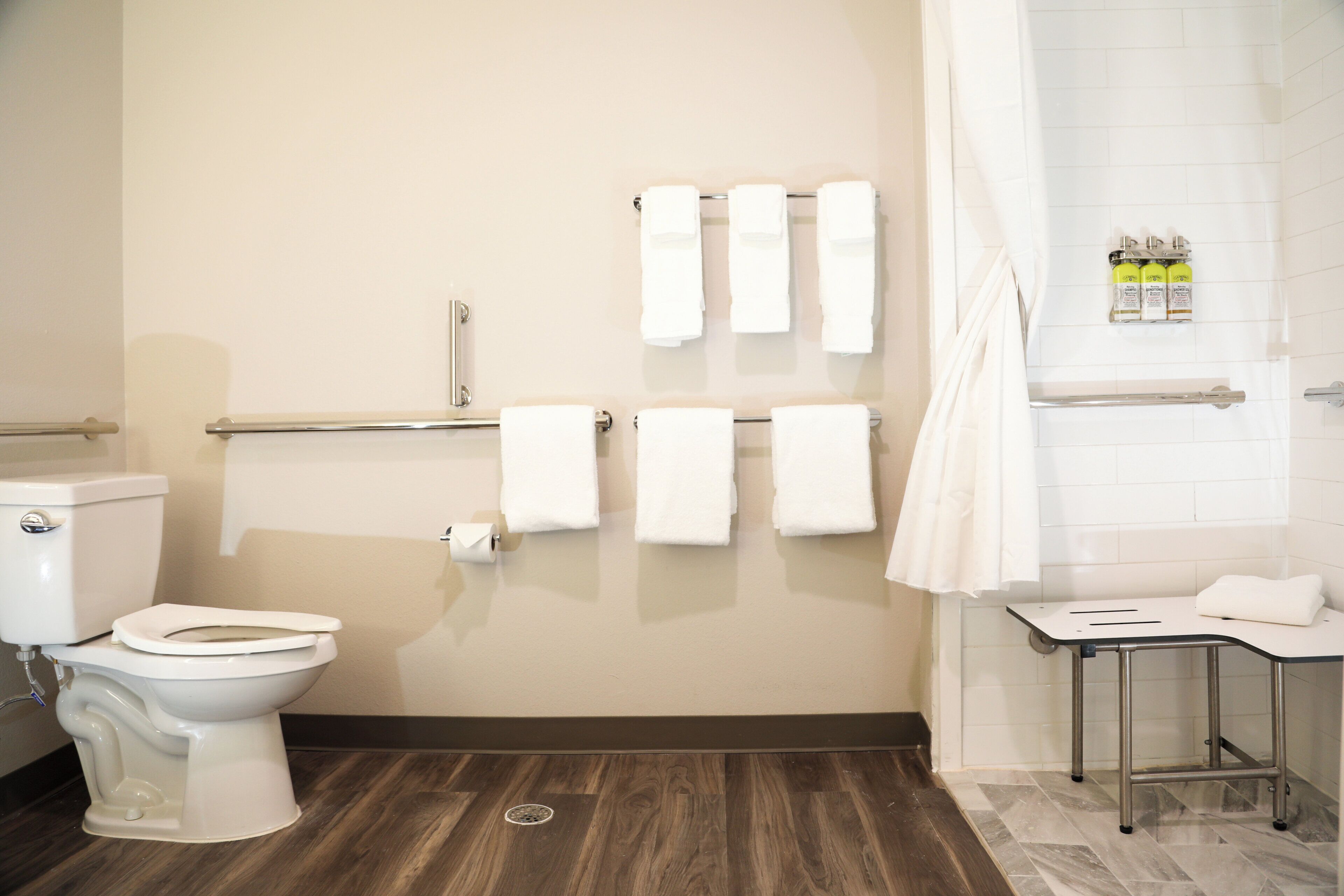 A bathroom with a toilet, a sink, a shower, and a towel rack with multiple towels.