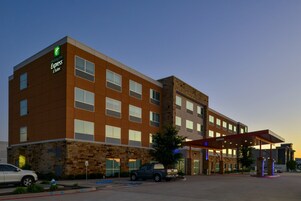Edificio de Holiday Inn Express con fachada de piedra, múltiples ventanas y entrada cubierta.