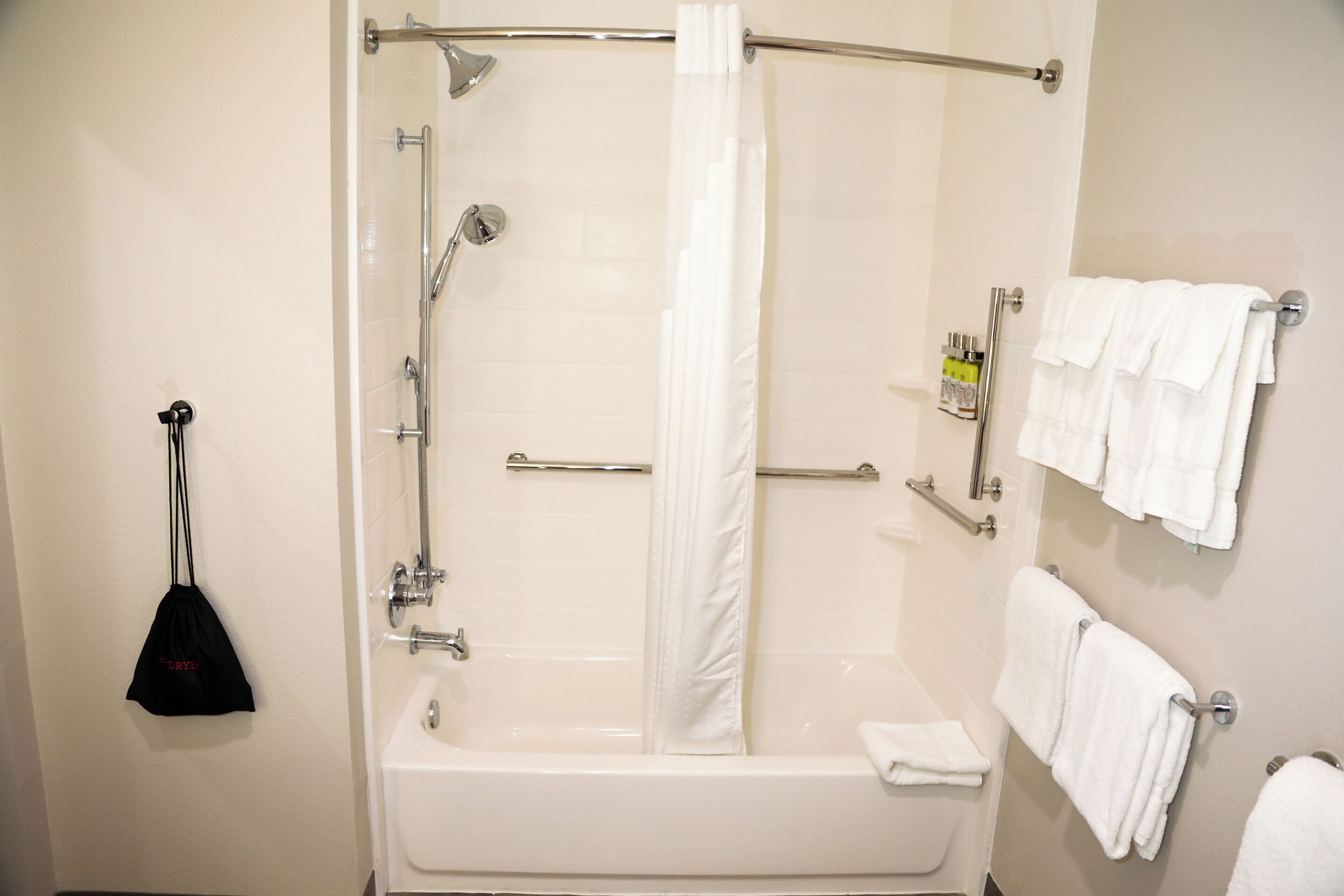 A bathroom with a bathtub, shower, and a towel rack with multiple towels.