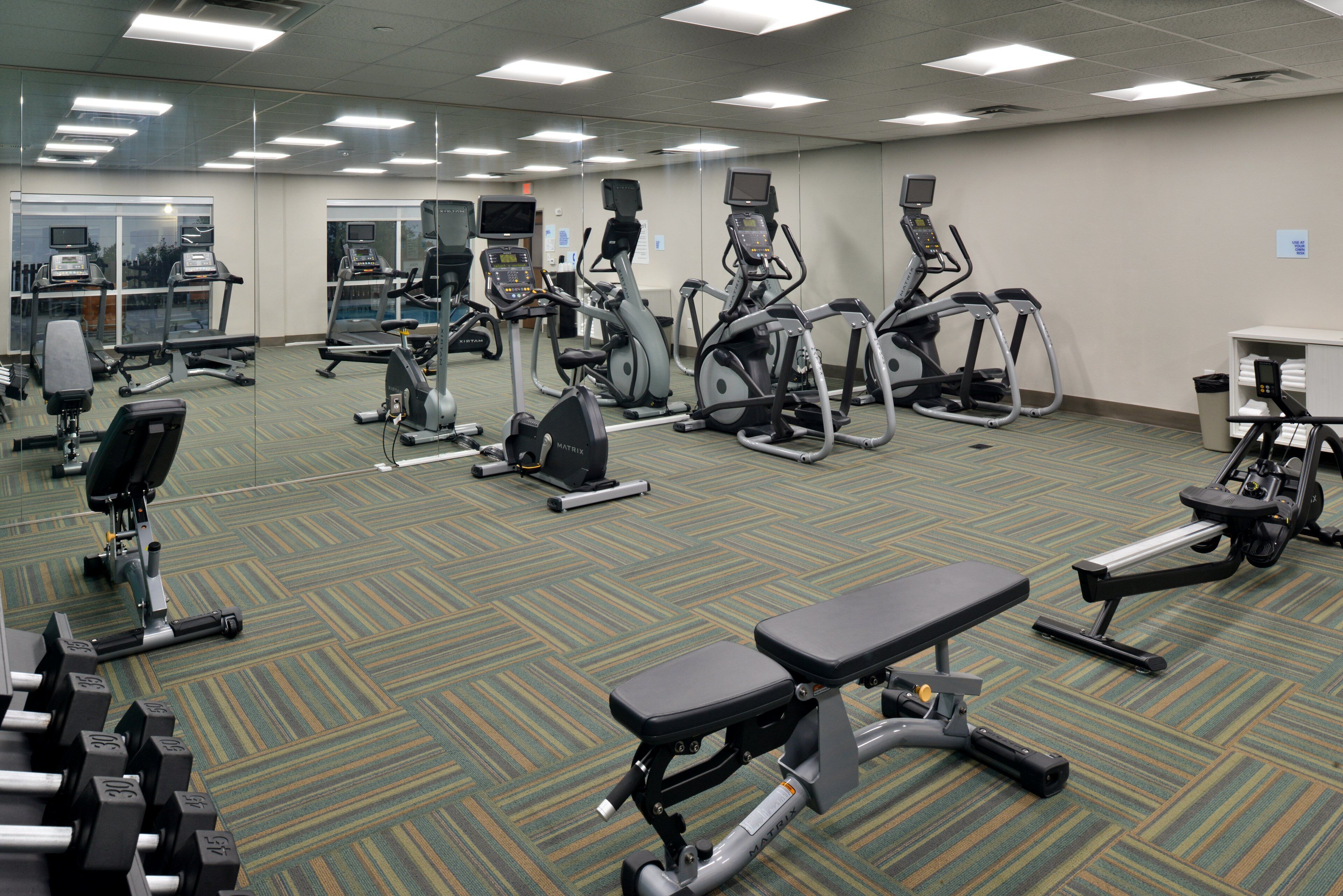 Un gimnasio con cintas de correr, elípticas y pesas sueltas.