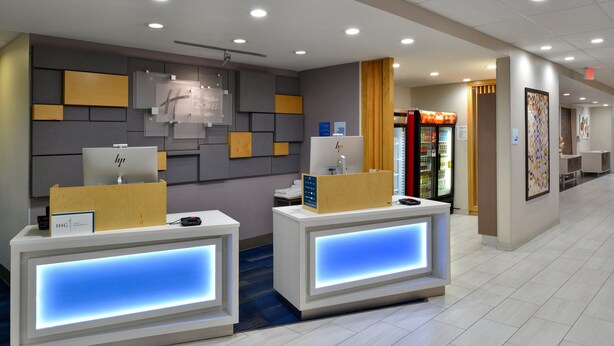 Een hotel receptie met twee balies, een klok aan de muur en een automaat.