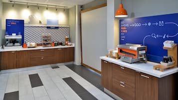 A modern kitchen area with a bakery section, a coffee machine, and a chalkboard with writing.