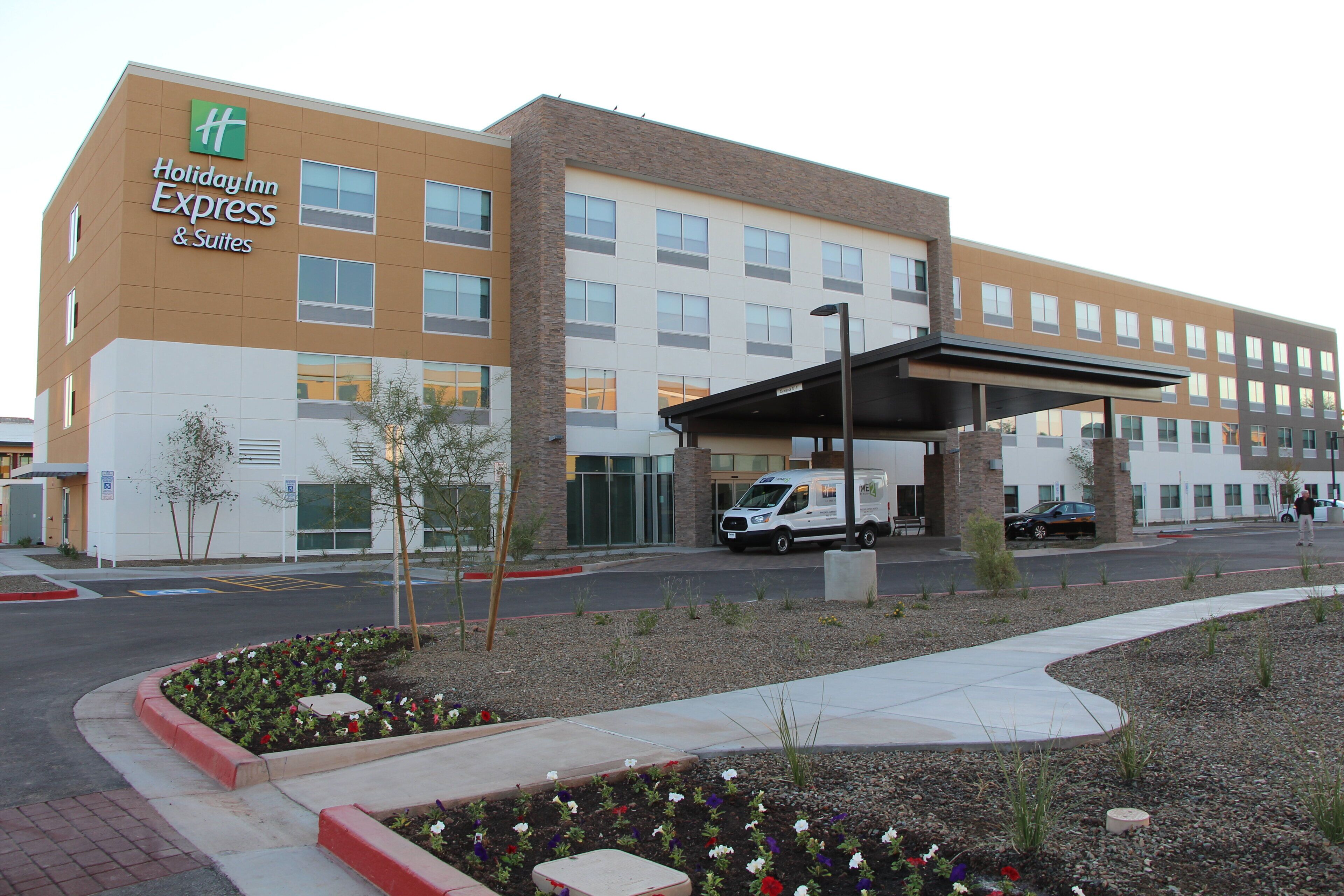 Un bâtiment de l’hôtel Holiday Inn Express & Suites, avec un espace de stationnement couvert et un fourgon garé devant.