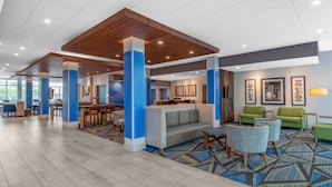 A spacious lobby with a modern design, featuring a central seating area with sofas and chairs, a patterned carpet, and a wooden ceiling. - Holiday Inn Express & Suites Phoenix - Airport North by IHG (Phoenix)
