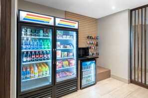 A vending area with three beverage dispensers, a microwave, and a small refrigerator. - Holiday Inn Express & Suites Phoenix - Airport North by IHG (Phoenix)