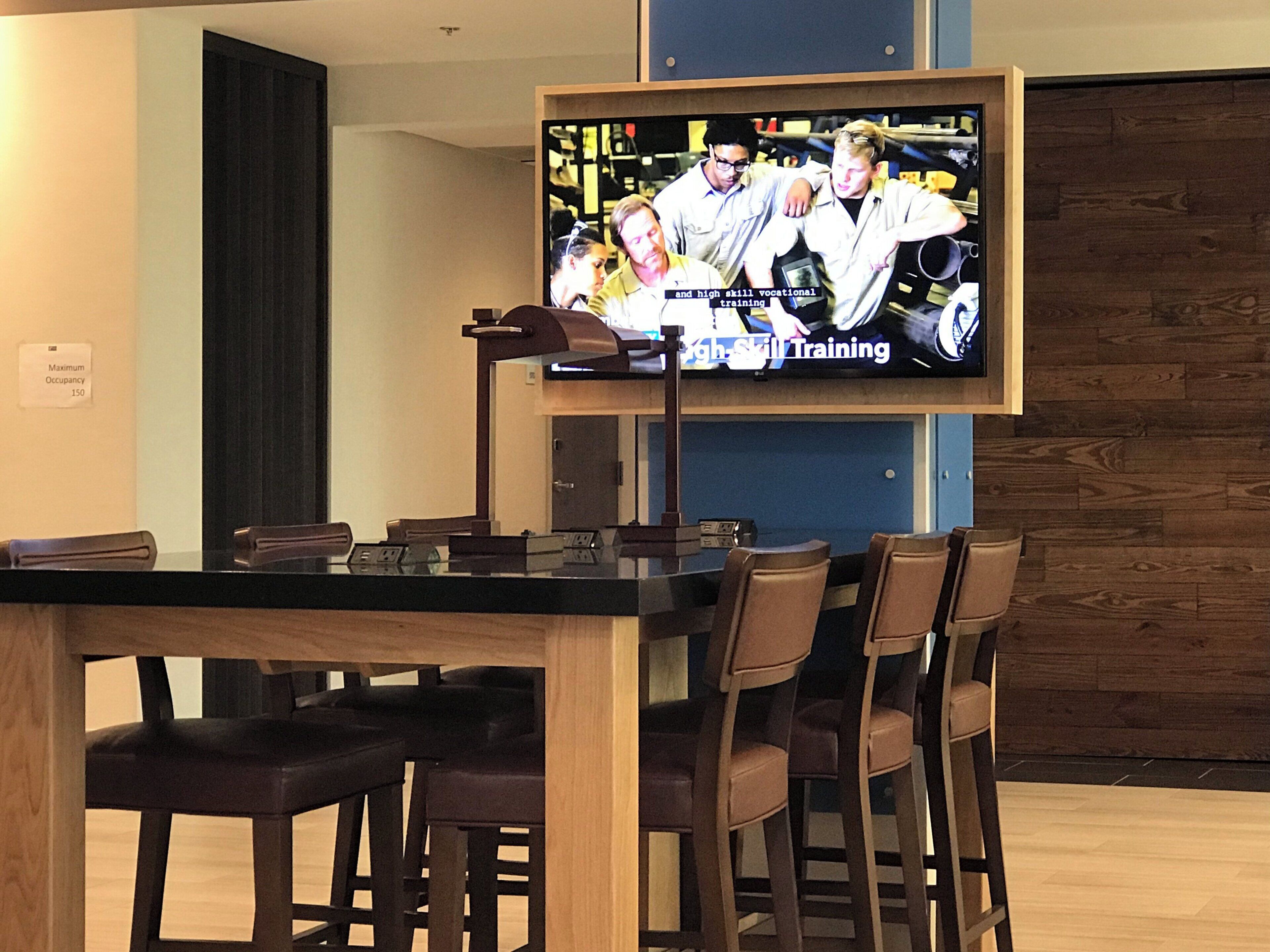A television mounted on a wall displaying a program about vocational training.