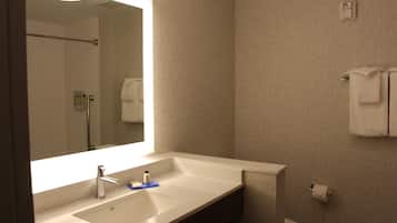 Un baño con un espejo grande, un lavamanos, un inodoro y un perchero para toallas.