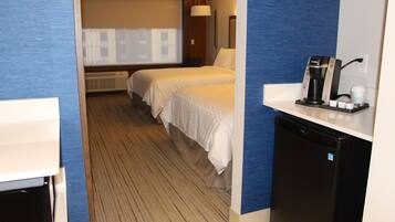 A hotel room with two beds, a small kitchenette, and a view of the cityscape.