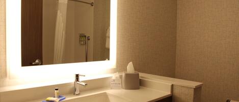 A bathroom with a white sink, a mirror, a towel dispenser, and a toilet.